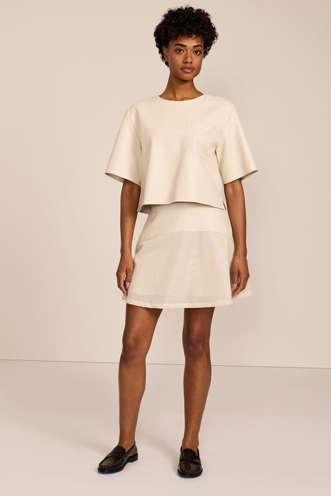 women's ivory faux leather short-sleeve top featuring a crew neckline, relaxed cropped silhouette and perforated chest pocket.