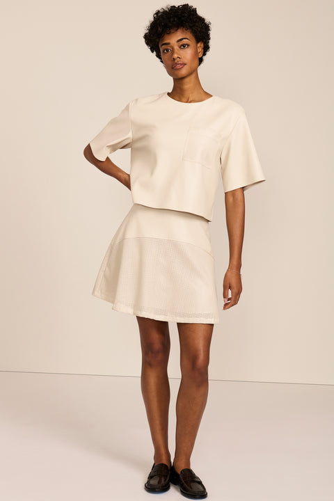 women's ivory faux leather short-sleeve top featuring a crew neckline, relaxed cropped silhouette and perforated chest pocket.