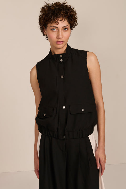 women's black sleeveless utility bomber vest featuring a stand collar, snap-front closure, flap pockets and elasticized hem.