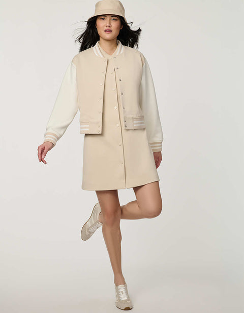 Woman wearing neutral Modern Varsity Jacket with contrast sleeves, ribbed trim, snap-front closure and welt pockets.