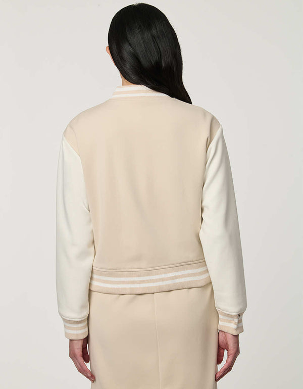 Woman wearing neutral Modern Varsity Jacket with contrast sleeves, ribbed trim, snap-front closure and welt pockets.