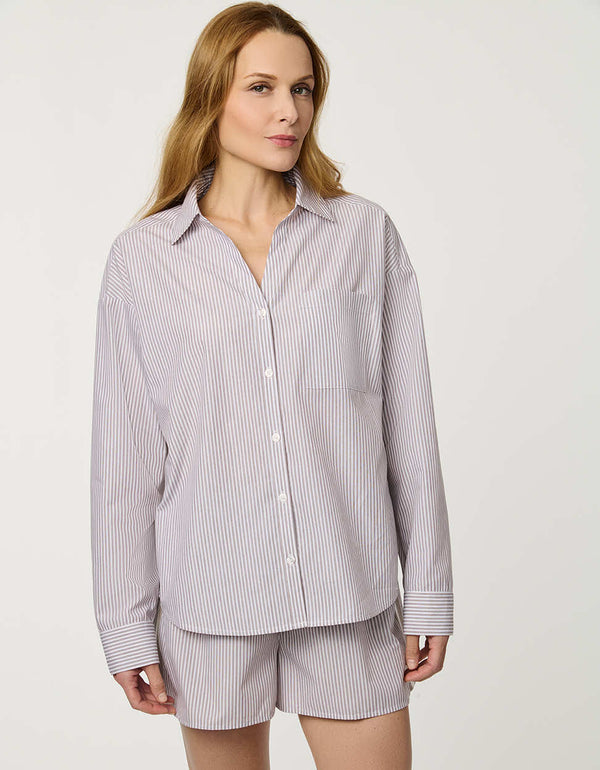 Woman wearing oversized Striped Poplin Boyfriend Shirt with button front and vertical side stripe.