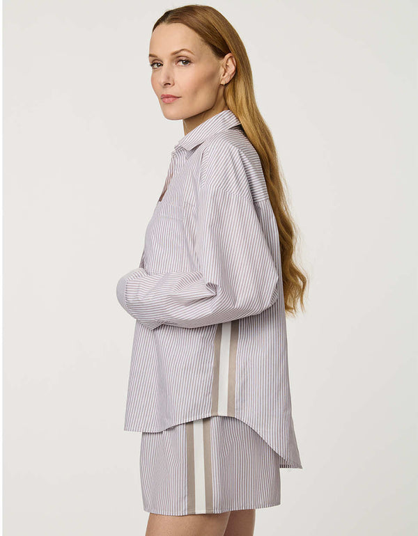 Woman wearing oversized Striped Poplin Boyfriend Shirt with button front and vertical side stripe.