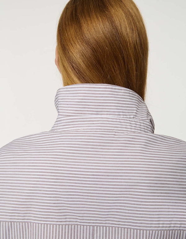 Woman wearing oversized Striped Poplin Boyfriend Shirt with button front and vertical side stripe.