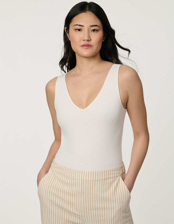 Women’s fitted jersey V-neck bodysuit in Bright White with sleeveless silhouette and smooth finish.