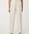 Woman wearing cream white pleated drawstring trousers with elastic waist and straight-leg silhouette.
