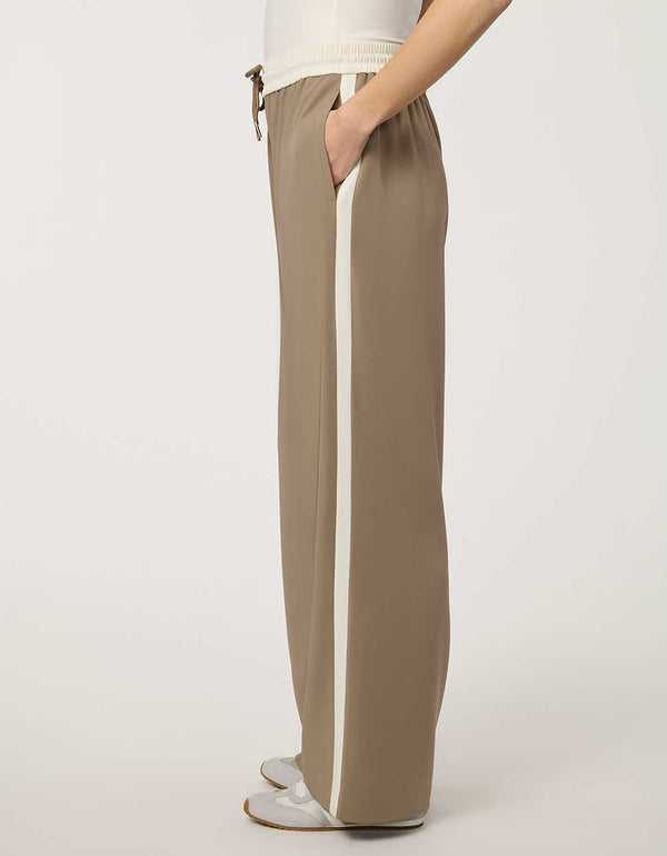 Woman wearing a pull-on wide leg trouser with side stripe in taupe, featuring elastic drawstring waistband and relaxed fit.