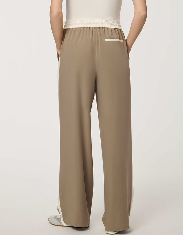 Woman wearing a pull-on wide leg trouser with side stripe in taupe, featuring elastic drawstring waistband and relaxed fit.