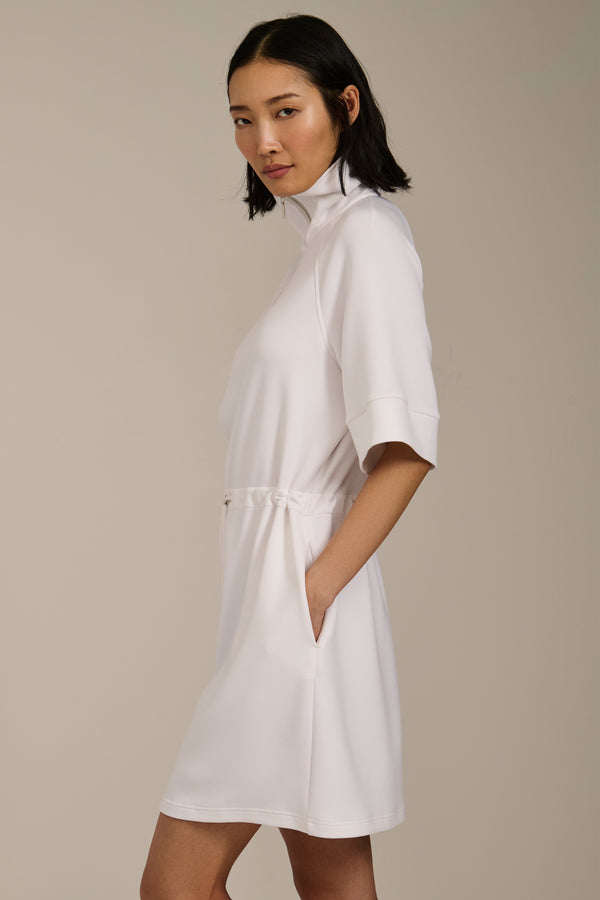 Woman wearing featherweight scuba quarter zip dress with drawcord waist, short sleeves, and side pockets.