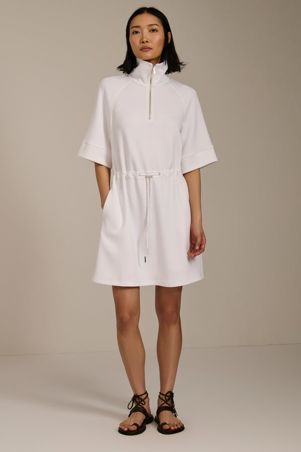 Woman wearing featherweight scuba quarter zip dress with drawcord waist, short sleeves, and side pockets.