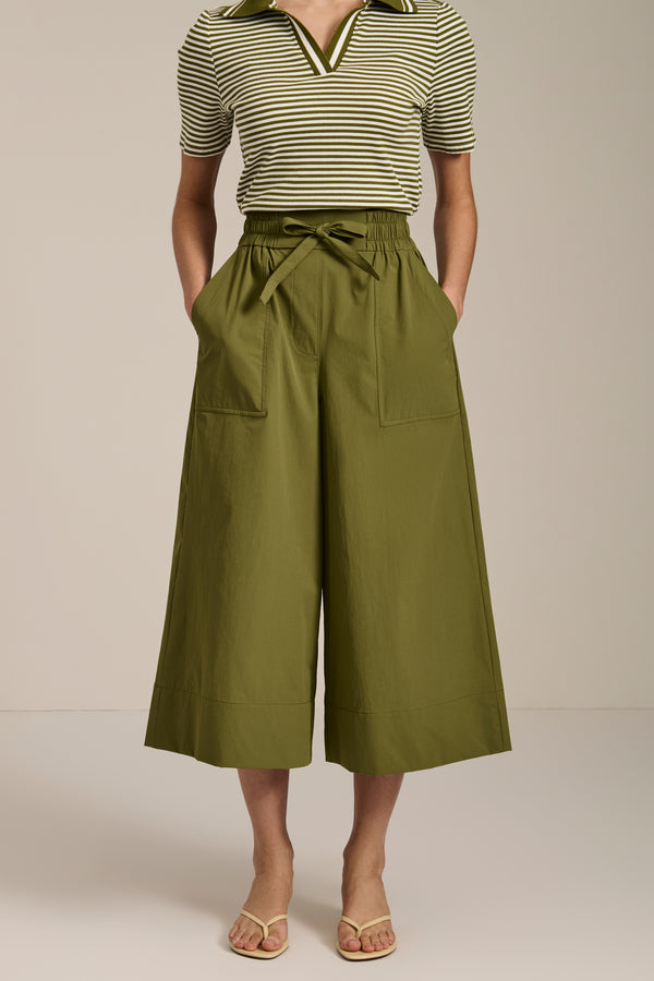 Woman wearing tech poplin wide leg culotte pants with elastic waist and patch pockets.