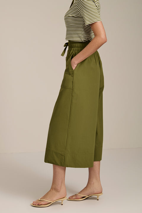 Woman wearing tech poplin wide leg culotte pants with elastic waist and patch pockets.