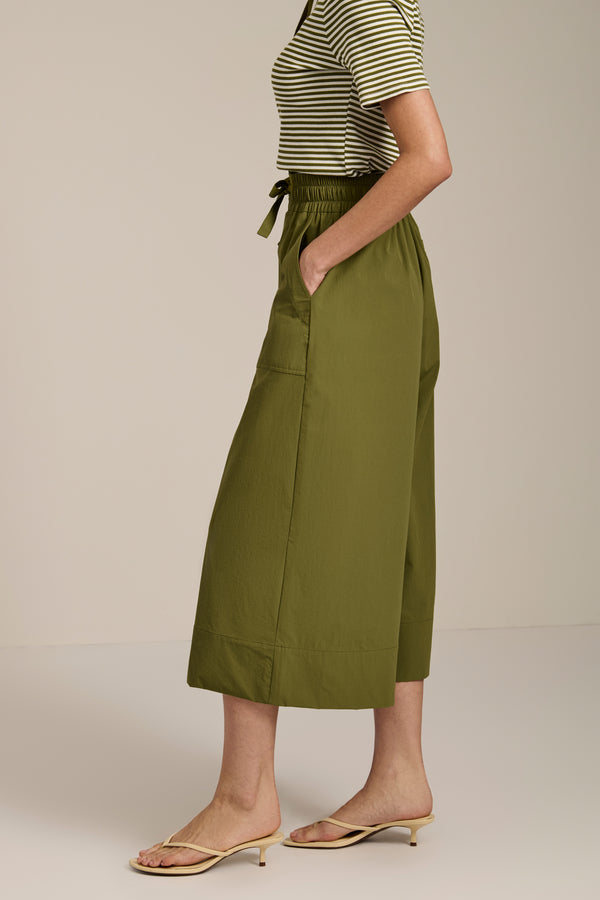 Woman wearing tech poplin wide leg culotte pants with elastic waist and patch pockets.