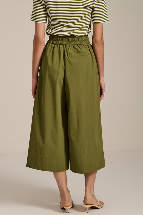 Woman wearing tech poplin wide leg culotte pants with elastic waist and patch pockets.