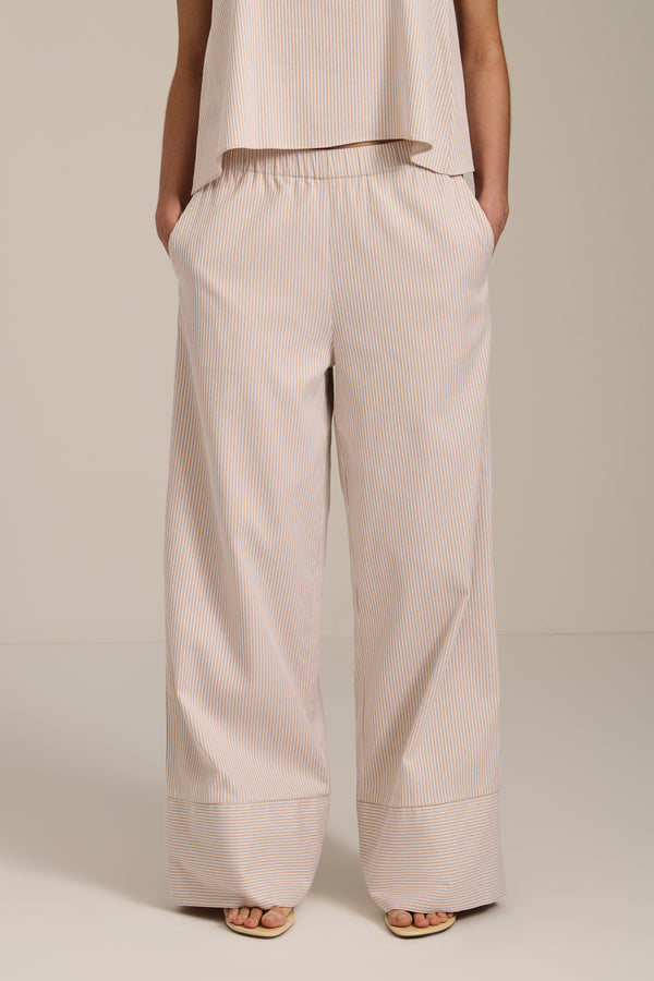 Woman wearing striped wide leg pants with elastic waistband and relaxed silhouette.