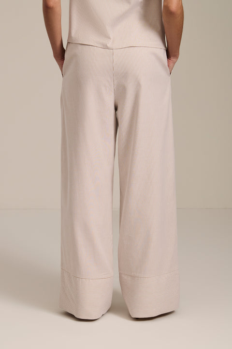 Woman wearing striped wide leg pants with elastic waistband and relaxed silhouette.