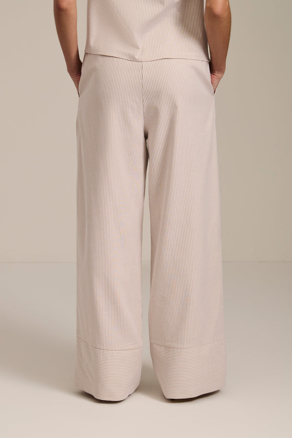 Woman wearing striped wide leg pants with elastic waistband and relaxed silhouette.
