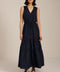 Woman wearing sleeveless navy maxi dress with V-neckline, drawcord waist, and pleated tiered skirt.