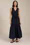 Woman wearing sleeveless navy maxi dress with V-neckline, drawcord waist, and pleated tiered skirt.