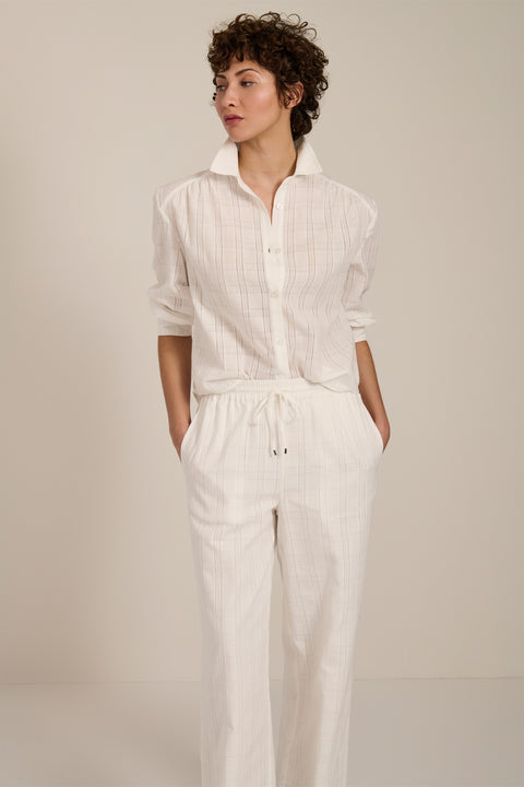 Woman wearing jacquard plaid button-up shirt with balloon sleeves and relaxed fit.