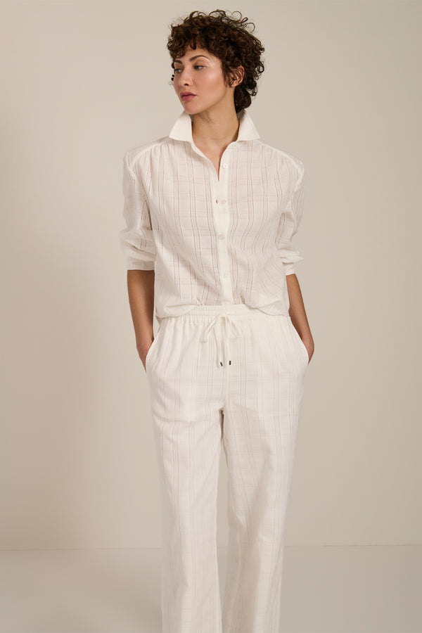 Woman wearing jacquard plaid button-up shirt with balloon sleeves and relaxed fit.
