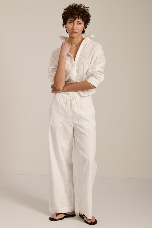 Woman wearing jacquard plaid button-up shirt with balloon sleeves and relaxed fit.