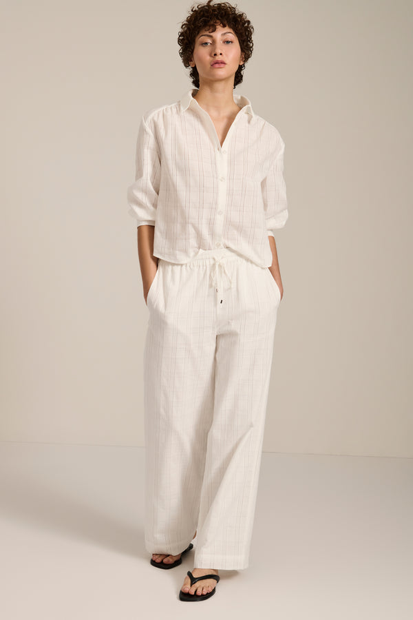 Woman wearing jacquard plaid button-up shirt with balloon sleeves and relaxed fit.