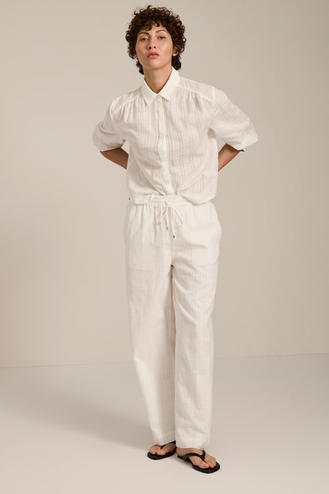 Woman wearing jacquard plaid button-up shirt with balloon sleeves and relaxed fit.