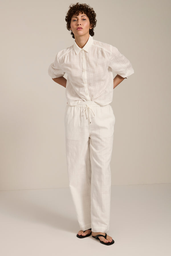 Woman wearing jacquard plaid button-up shirt with balloon sleeves and relaxed fit.