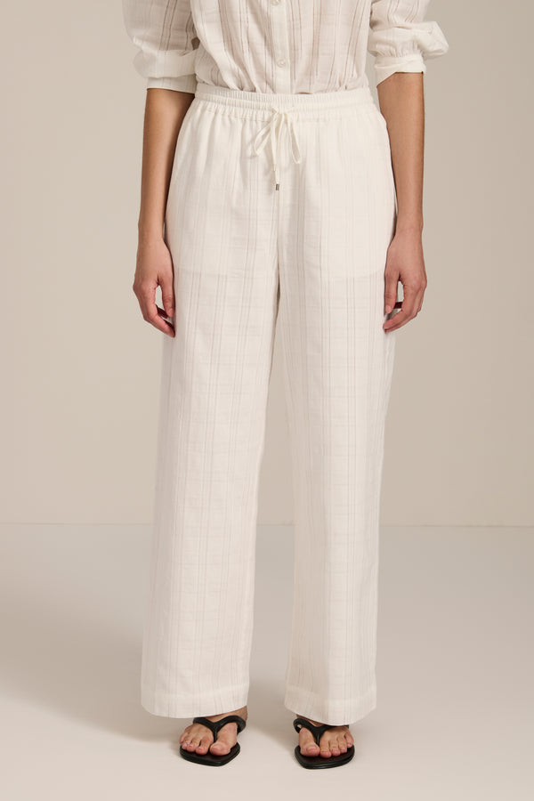 Woman wearing jacquard plaid relaxed pants with elastic drawstring waist and straight leg silhouette.