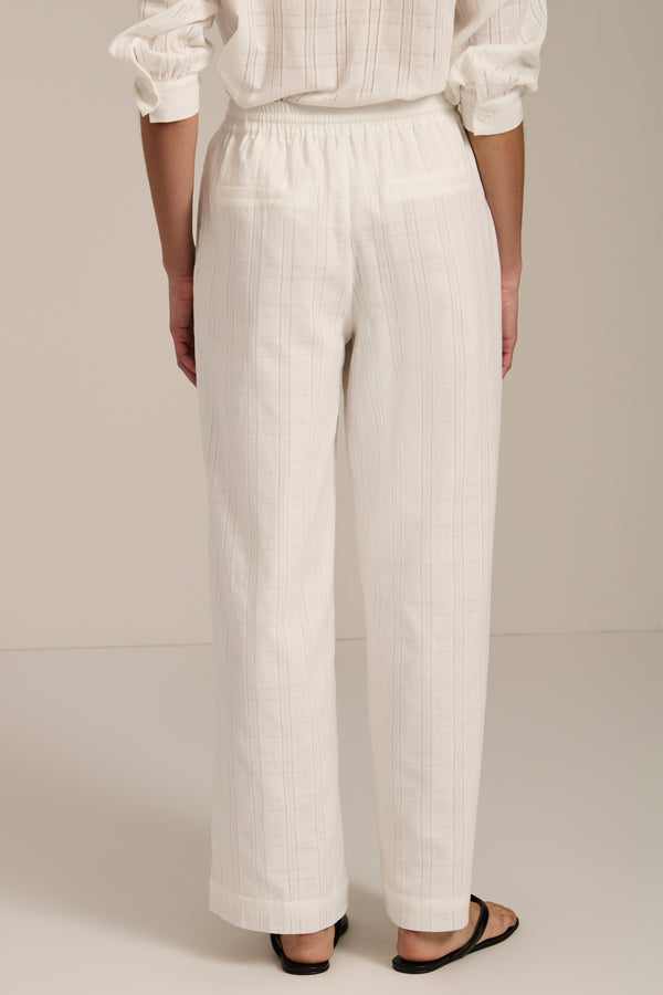 Woman wearing jacquard plaid relaxed pants with elastic drawstring waist and straight leg silhouette.