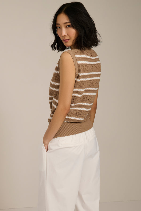 Woman wearing sleeveless striped pointelle knit top with textured openwork detailing.