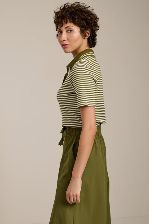 Woman wearing striped short sleeve polo sweater with collared neckline and fitted silhouette.