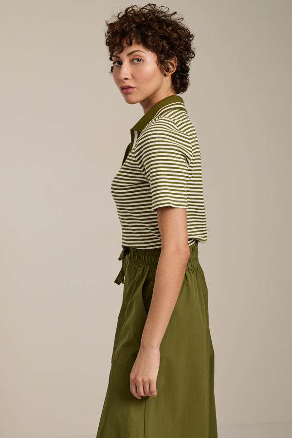 Woman wearing striped short sleeve polo sweater with collared neckline and fitted silhouette.