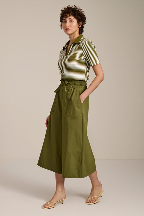 Woman wearing striped short sleeve polo sweater with collared neckline and fitted silhouette.