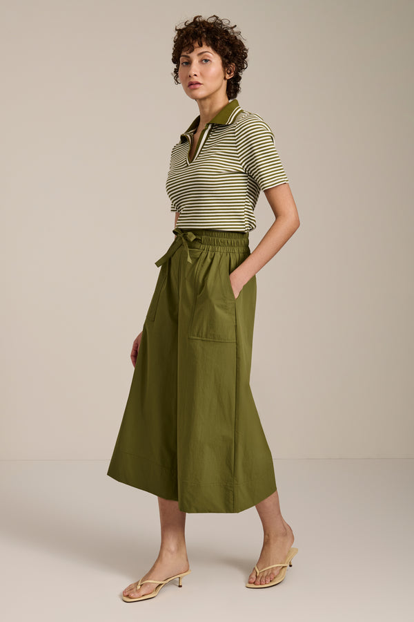 Woman wearing striped short sleeve polo sweater with collared neckline and fitted silhouette.