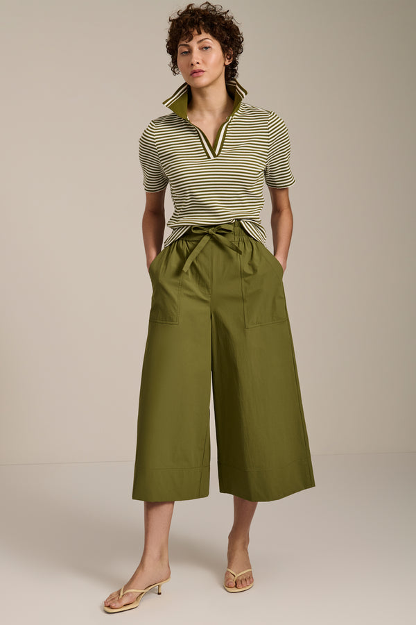 Woman wearing striped short sleeve polo sweater with collared neckline and fitted silhouette.