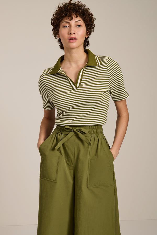 Woman wearing striped short sleeve polo sweater with collared neckline and fitted silhouette.